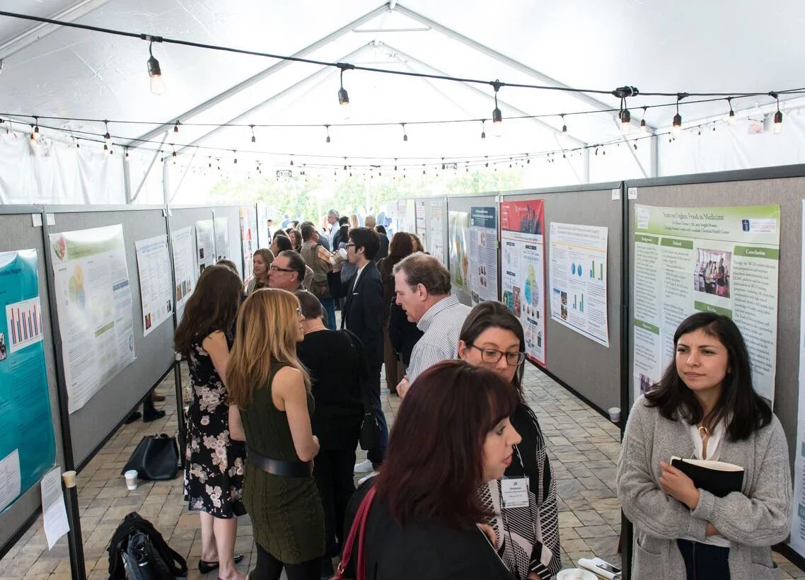 Conference attendees view a row of research posters