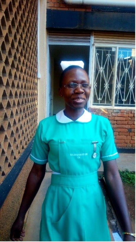 Photograph of Ms. Kevin Nalubwama standing in a in a turquoise dress outside of a building