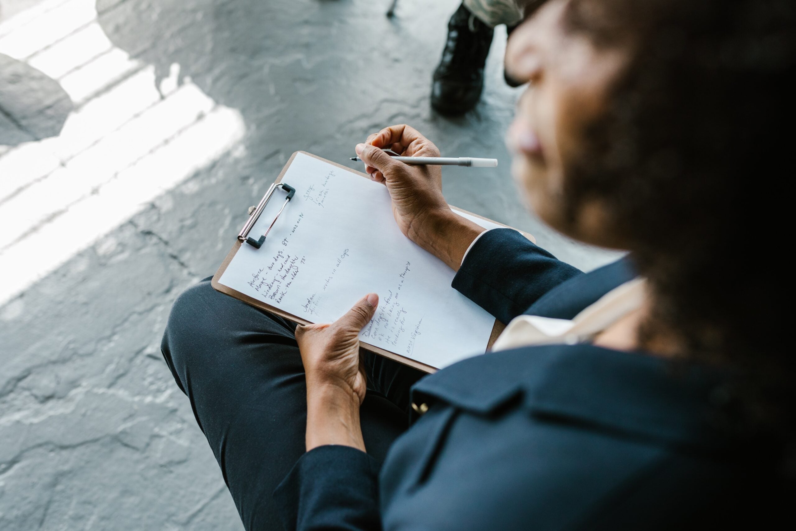 Mental health professional writing notes on a piece of paper attached to a clipboard.