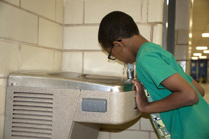 A student getting a drink of water at a school water fountain