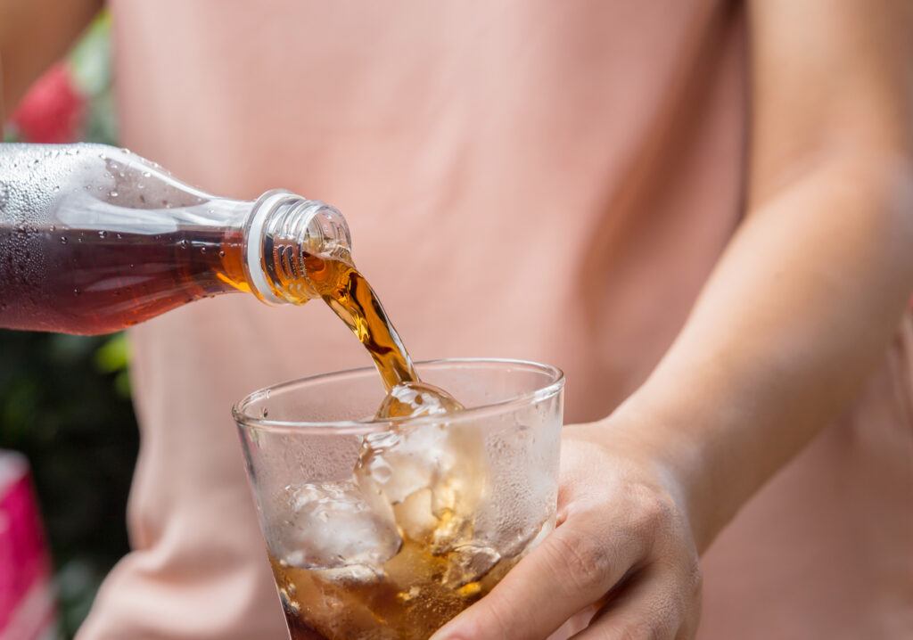 A person pouring a glass of soda