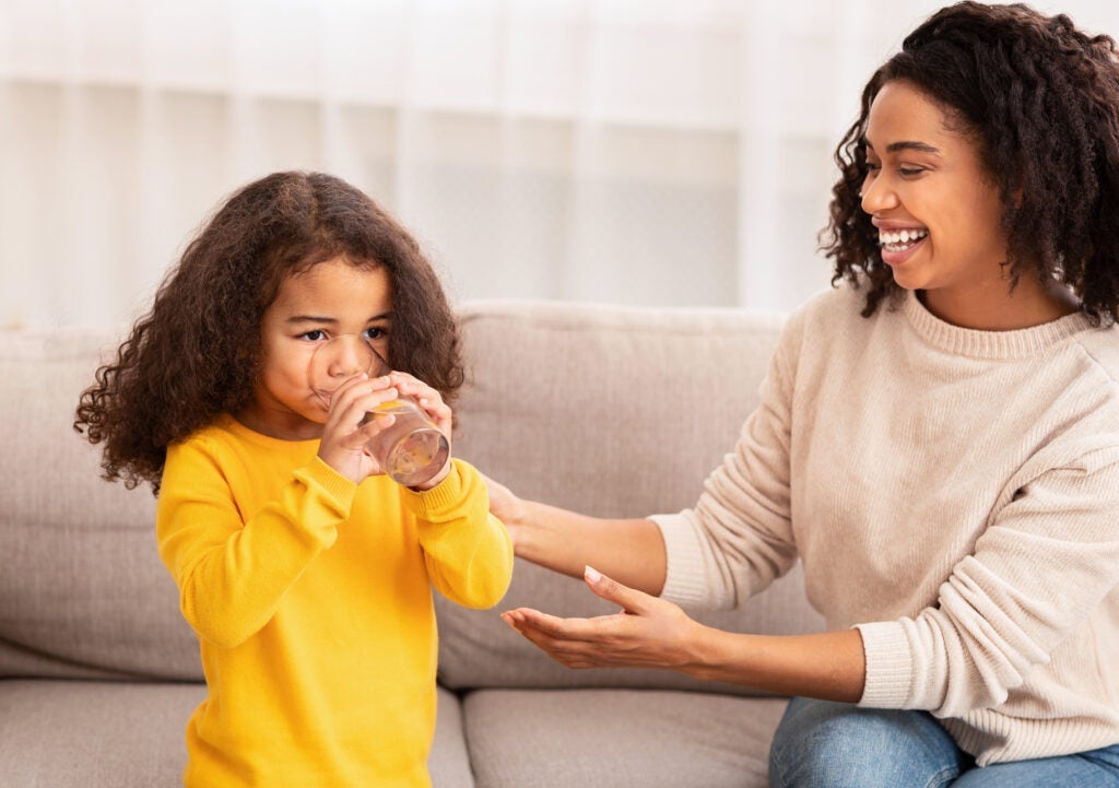 Mom giving young daughter a glass of water