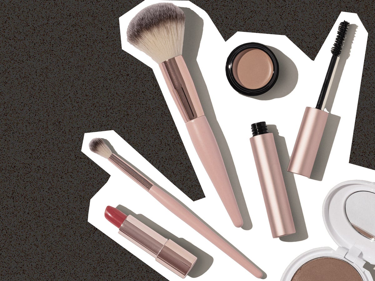 Miscellaneous rose gold cosmetic products are placed against a grey-speckled background.