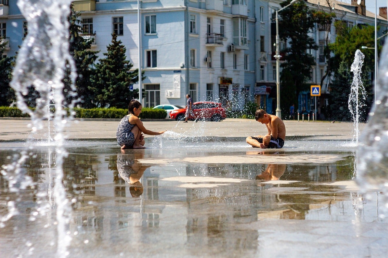 Children playing in sprinklers on a hot day in the city.