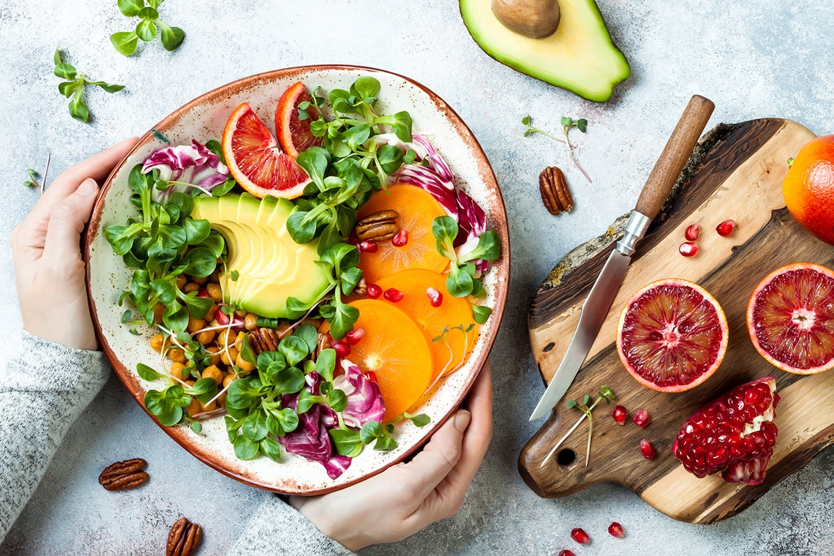 a bowl of healthy plant foods, including avocado, sprouts, and other vegetables and fruits