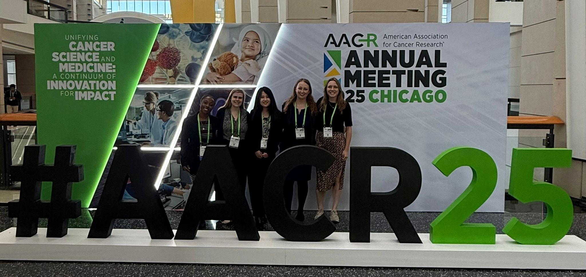A group of people gathered in front of an AACR Annual Meeting banner.
