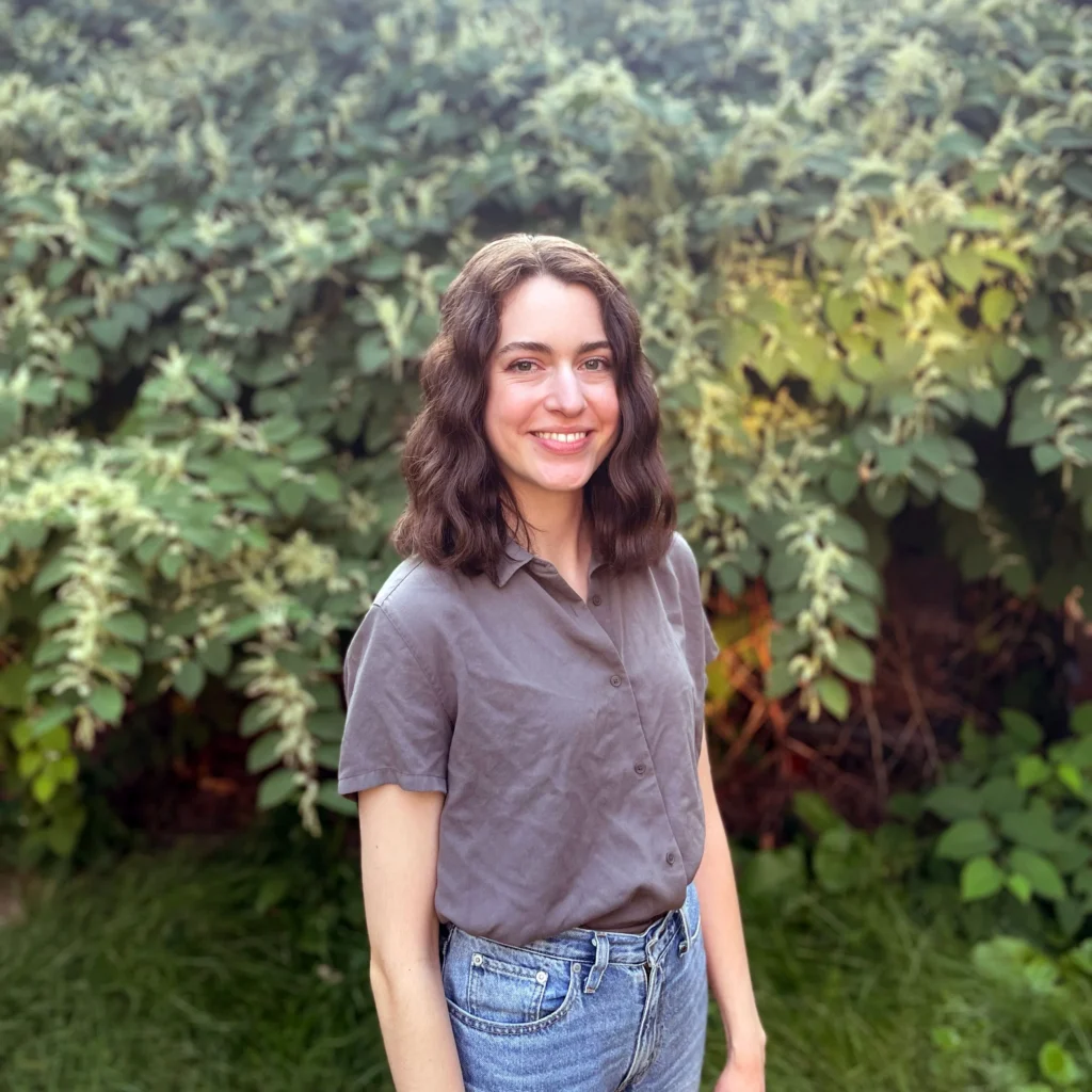 Kerry McGown posing in front of greenery. 