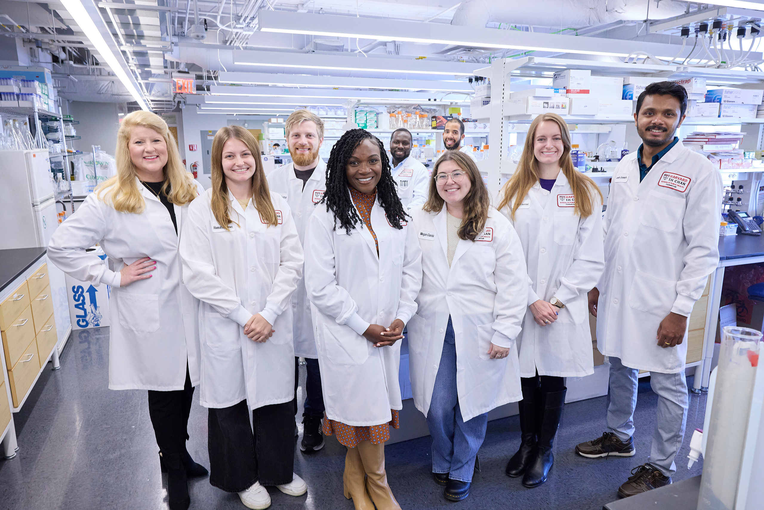 Corbett Lab group standing by the benches in the lab, all wearing coats.