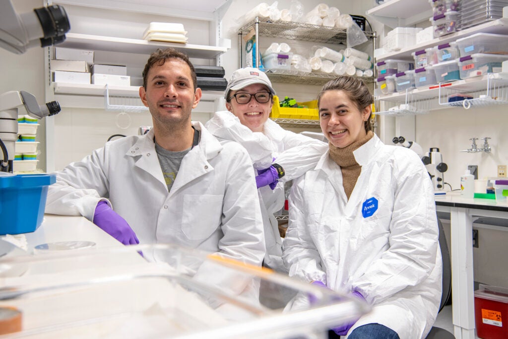 Emre left, Alexandra right with a student center posing for a photo by the microscope area