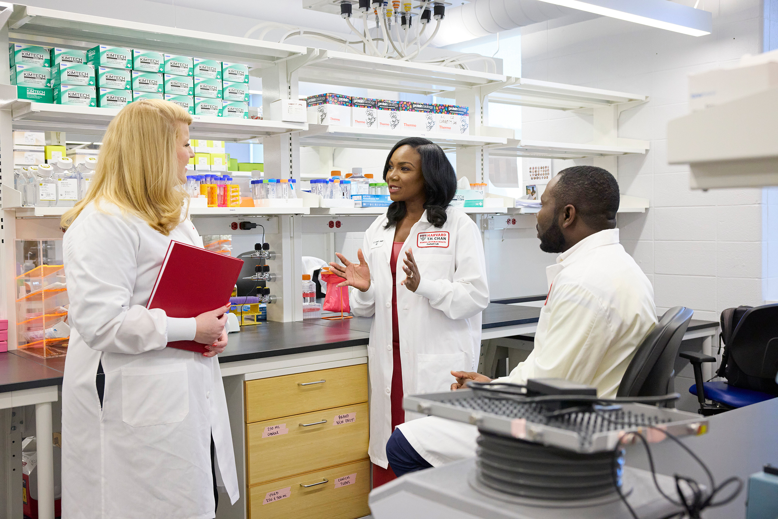 Kizzmekia talking to Sydney and Christian in the lab