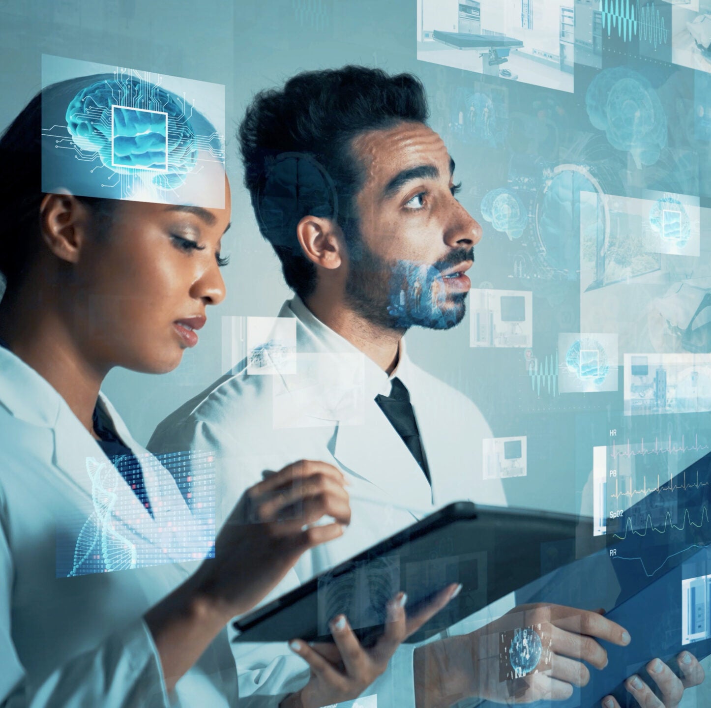 Two doctors wearing scrubs and holding tablets looking at holograms of medical charts