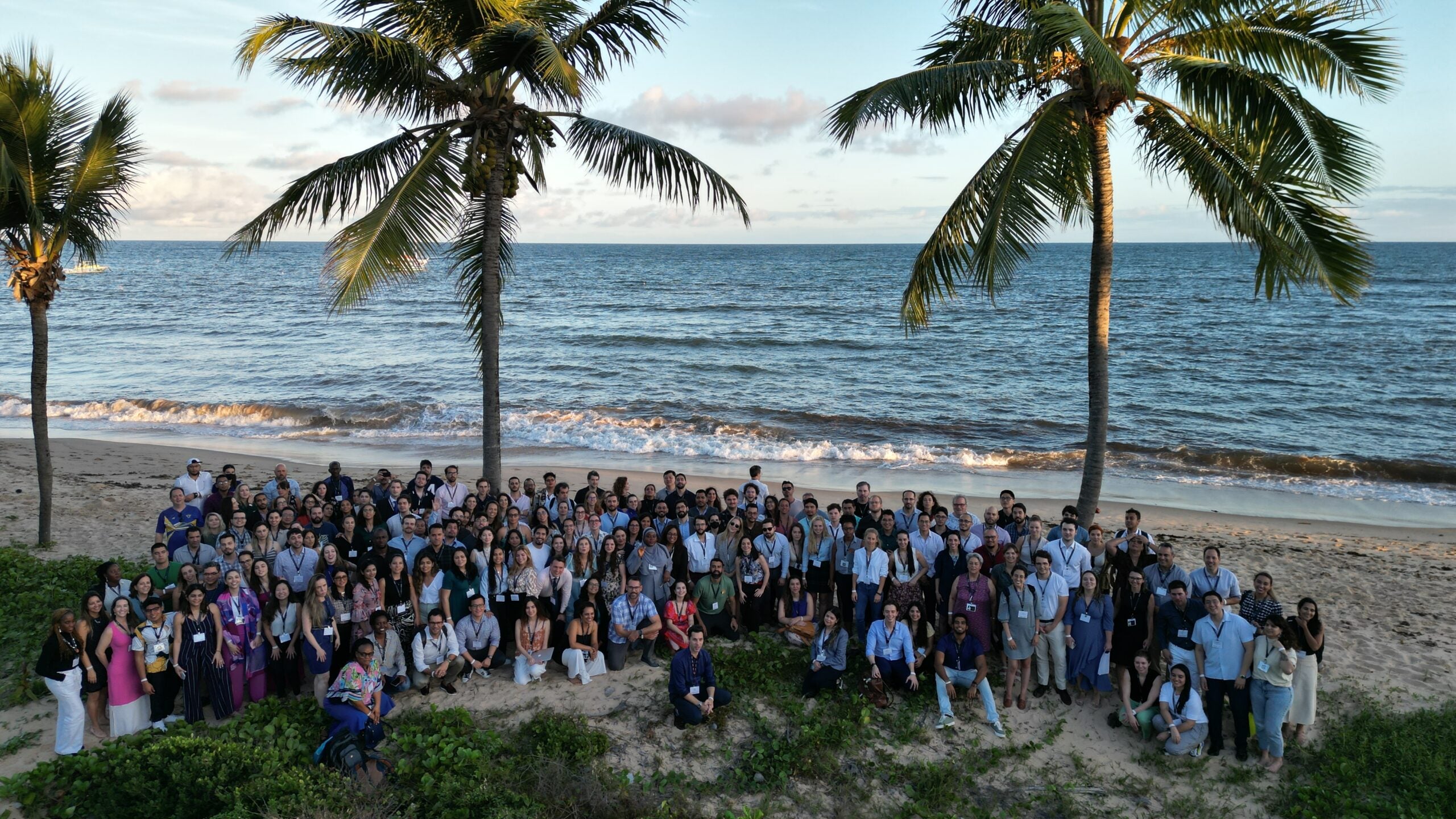 Group photo of PPCR students on a beach in Brazil, as the sun is about to set