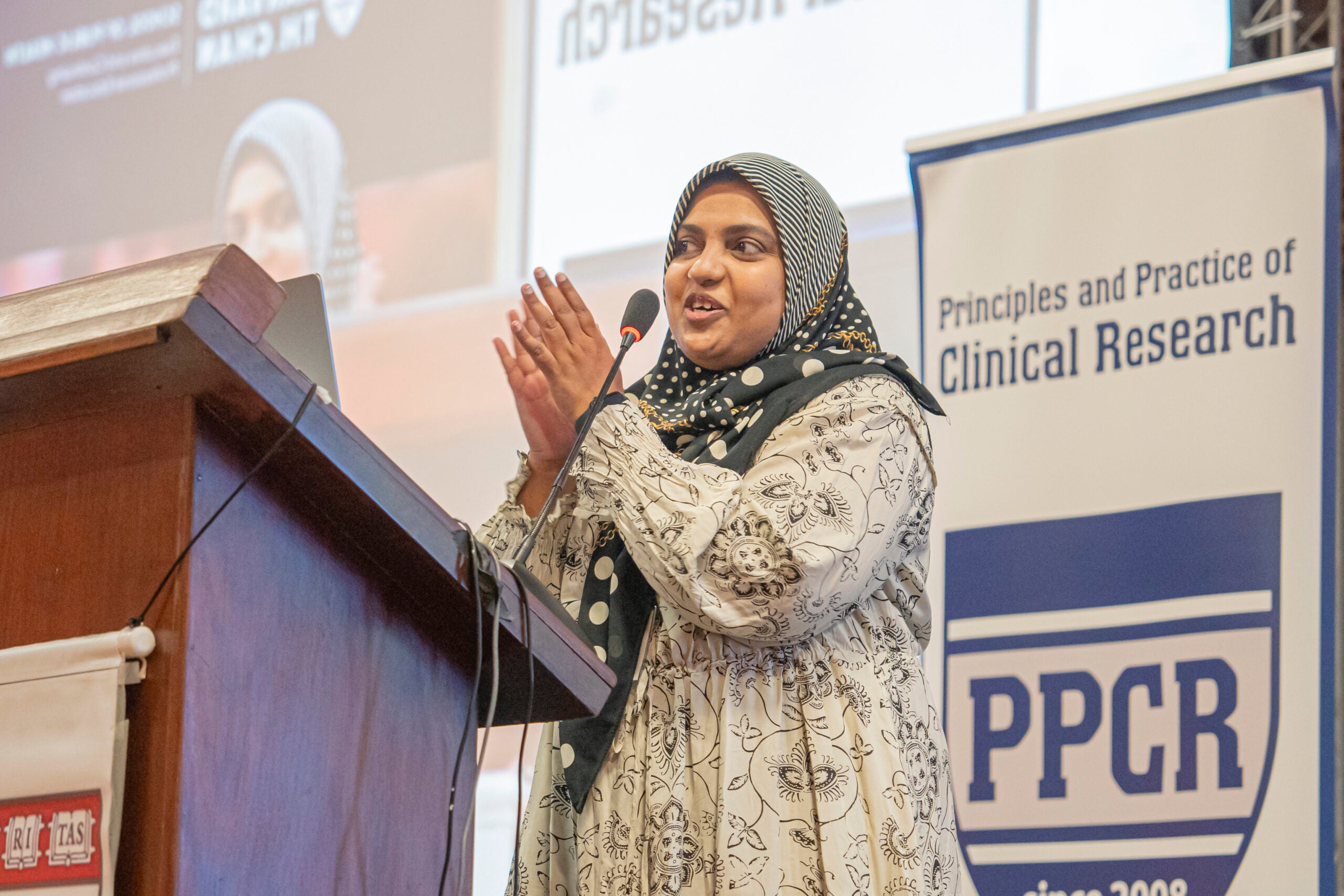 PPCR student clapping as she stands behind a podium and presents to a crowd