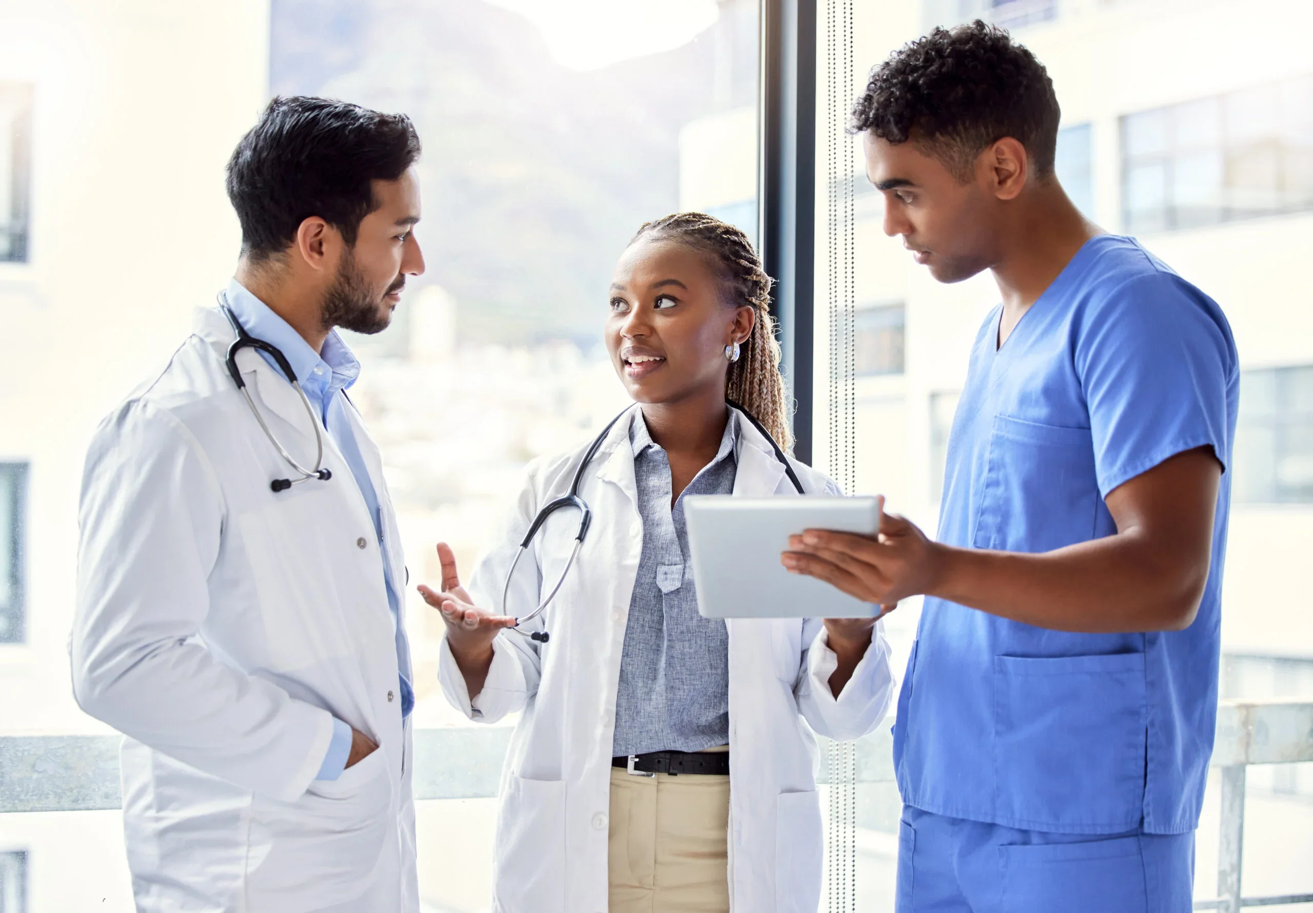 Two doctors and a nurse standing in front of a window, talking to one another