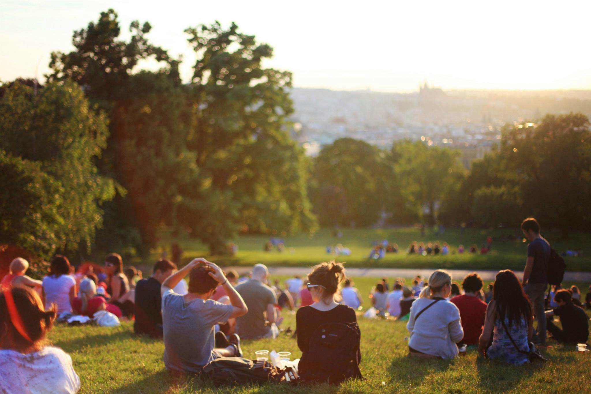 People sitting on a hill watching a sunset