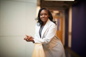 Kizzmekia Corbett, leaning on the railing in the hallway leading to her lab at the Chan School of Public Health