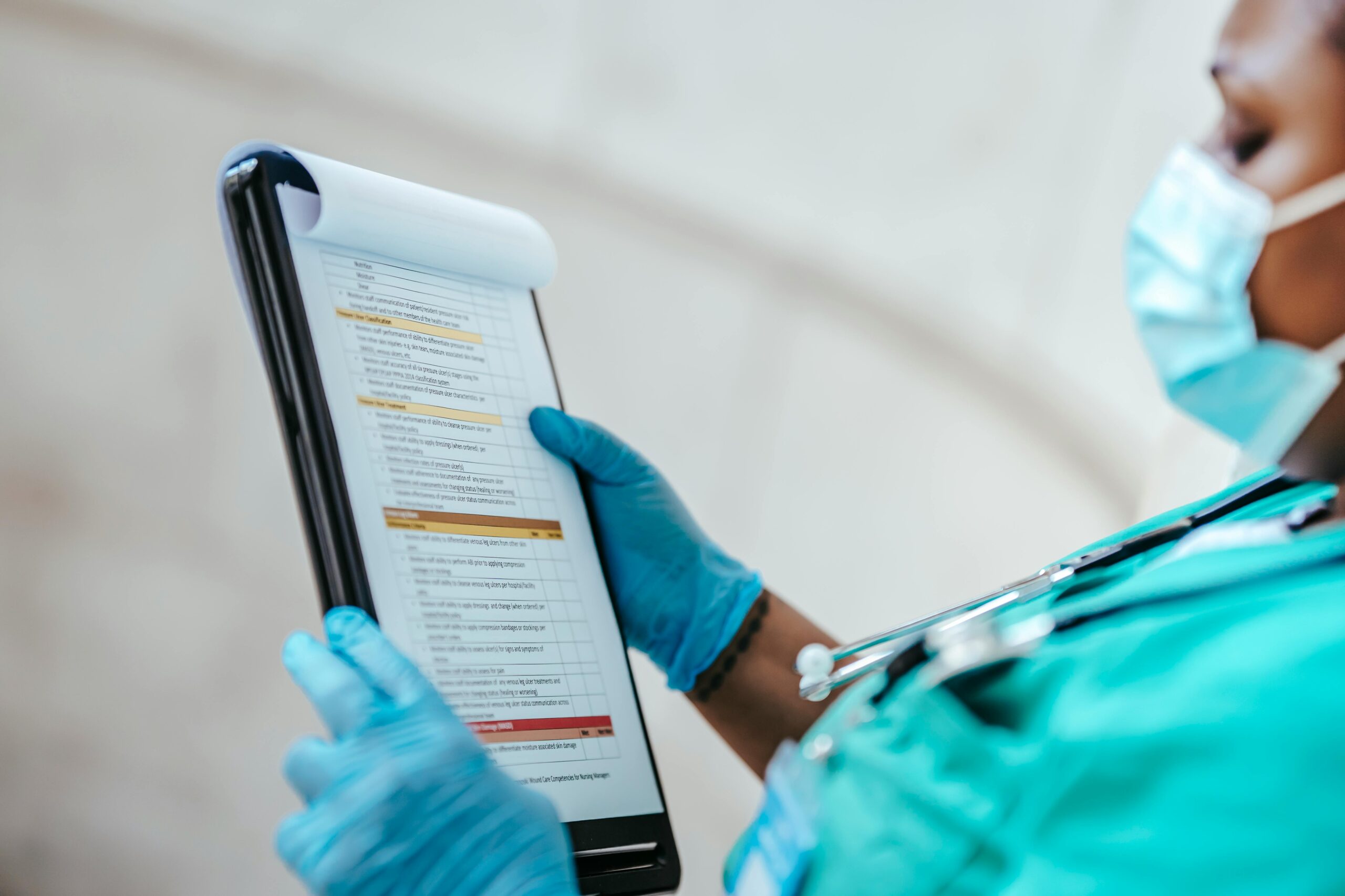 The profile of a masked medical professional holding a clipboard with notes.