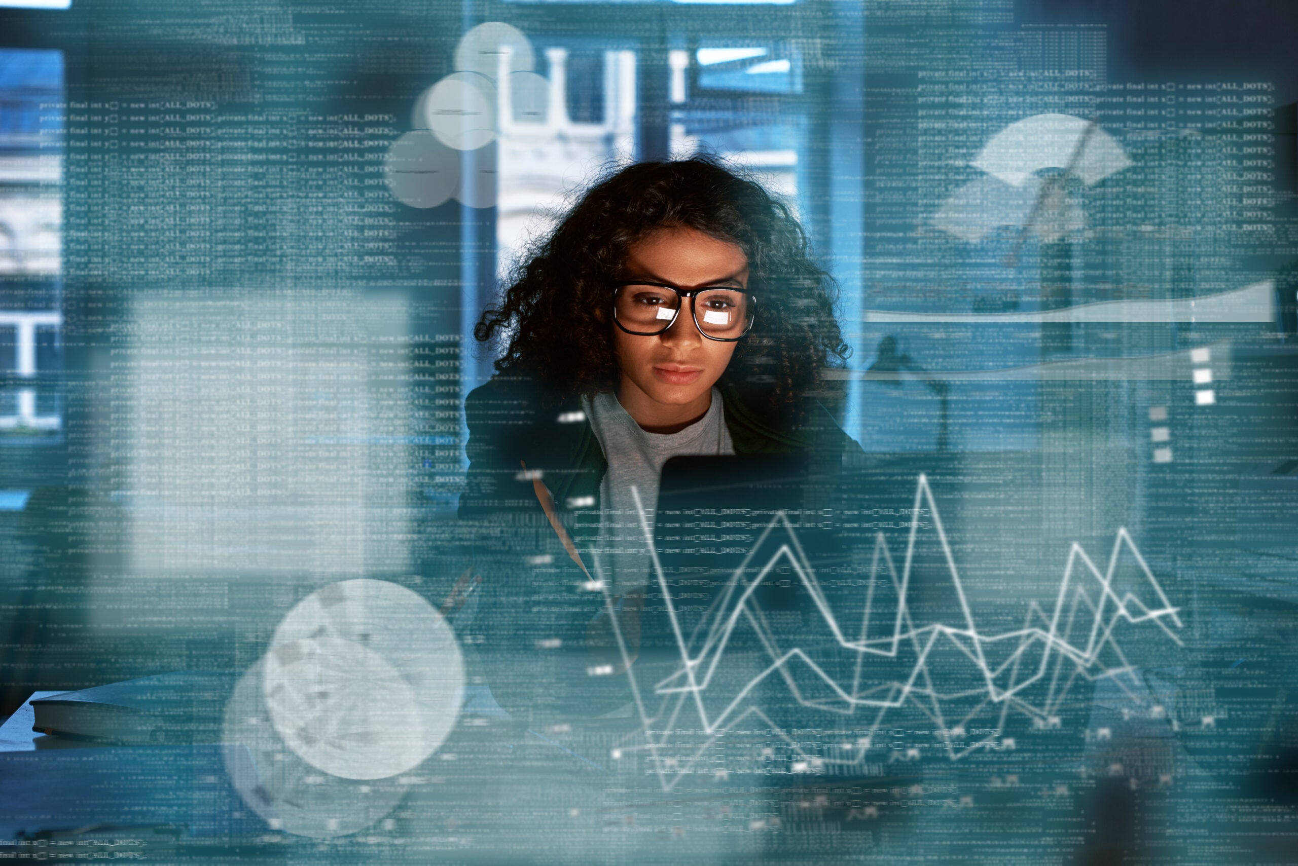 Young woman in glasses looking at various statistical models on a computer.