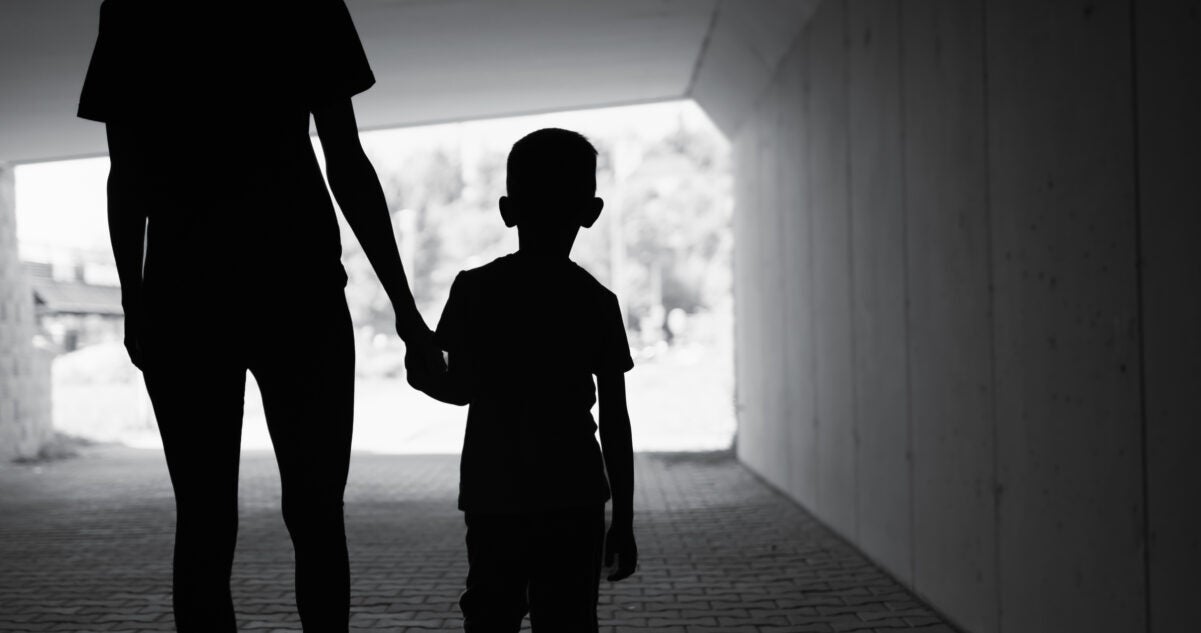 Black & white silhouette photo of woman holding boy's hand, from rear