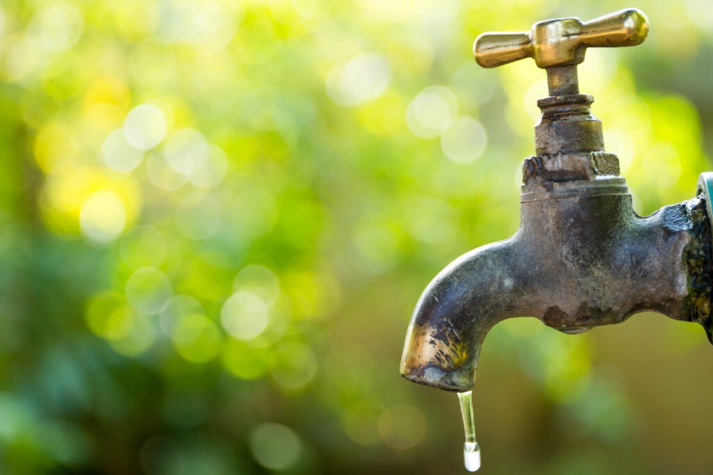 Brass water tap in nature background.