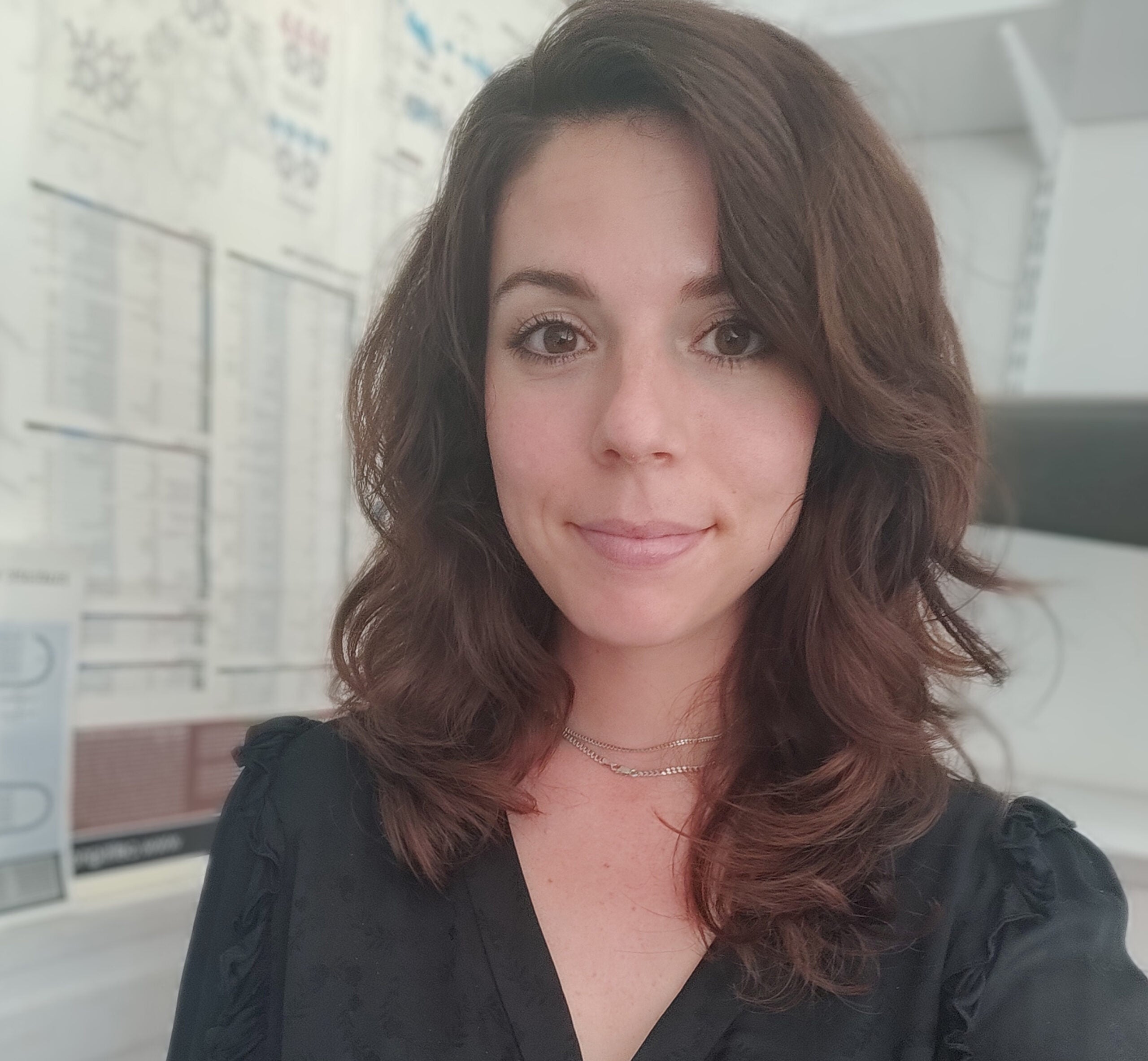 Gretchen in front of a white indoor background, wearing a black blouse.