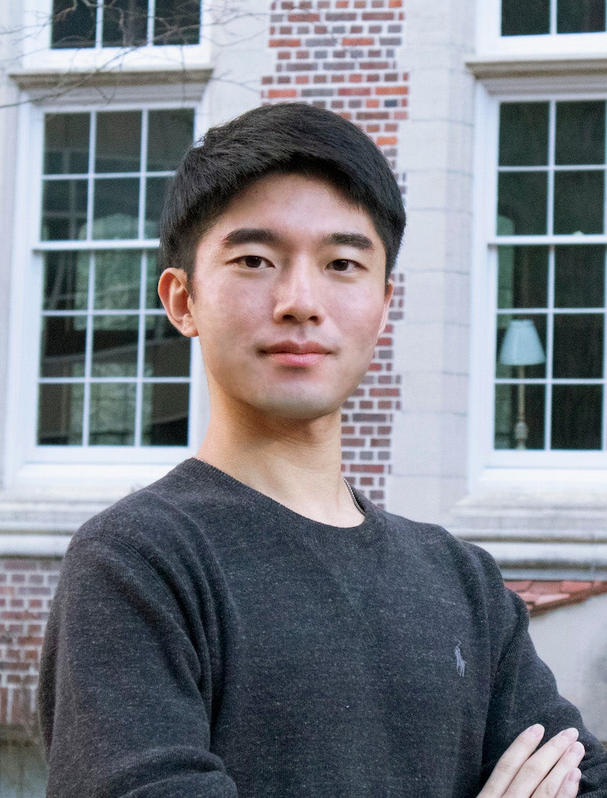a headshot of Dr. Heejun Shin. His arms are crossed on his chest and he wears a long sleeve grey sweater