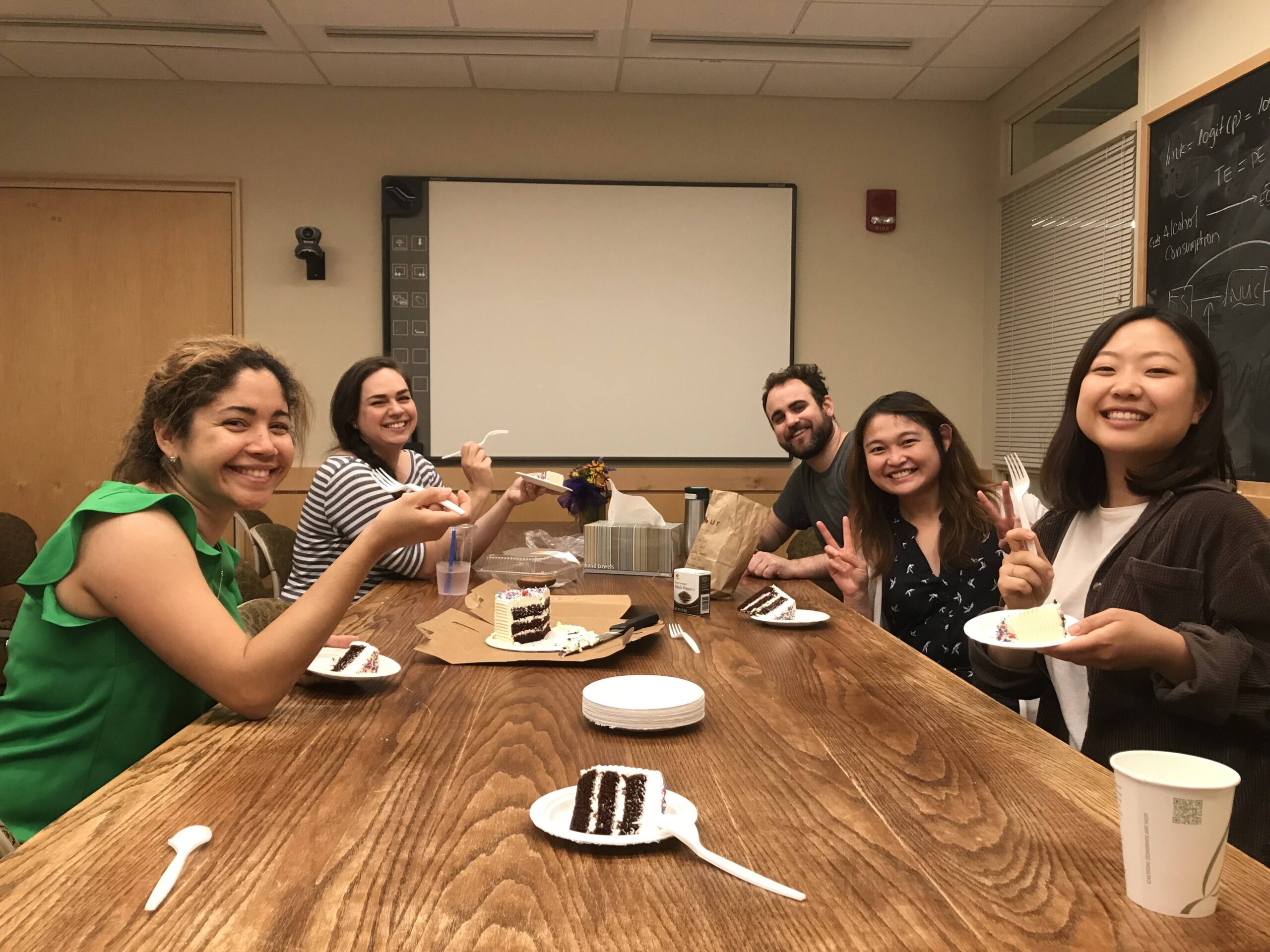 A group of students sitting at a table eating cake.