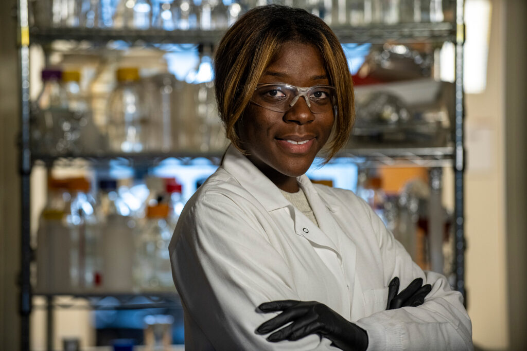 Wirth lab member in a white lab coat and gloves. 