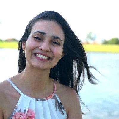 Natália wearing a flowered blouse before a lake.