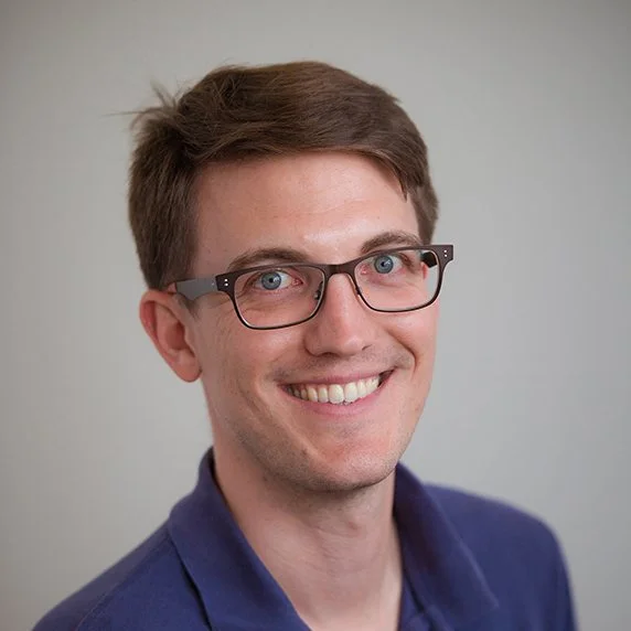 Headshot of Scott Olesen in front of a grey background.