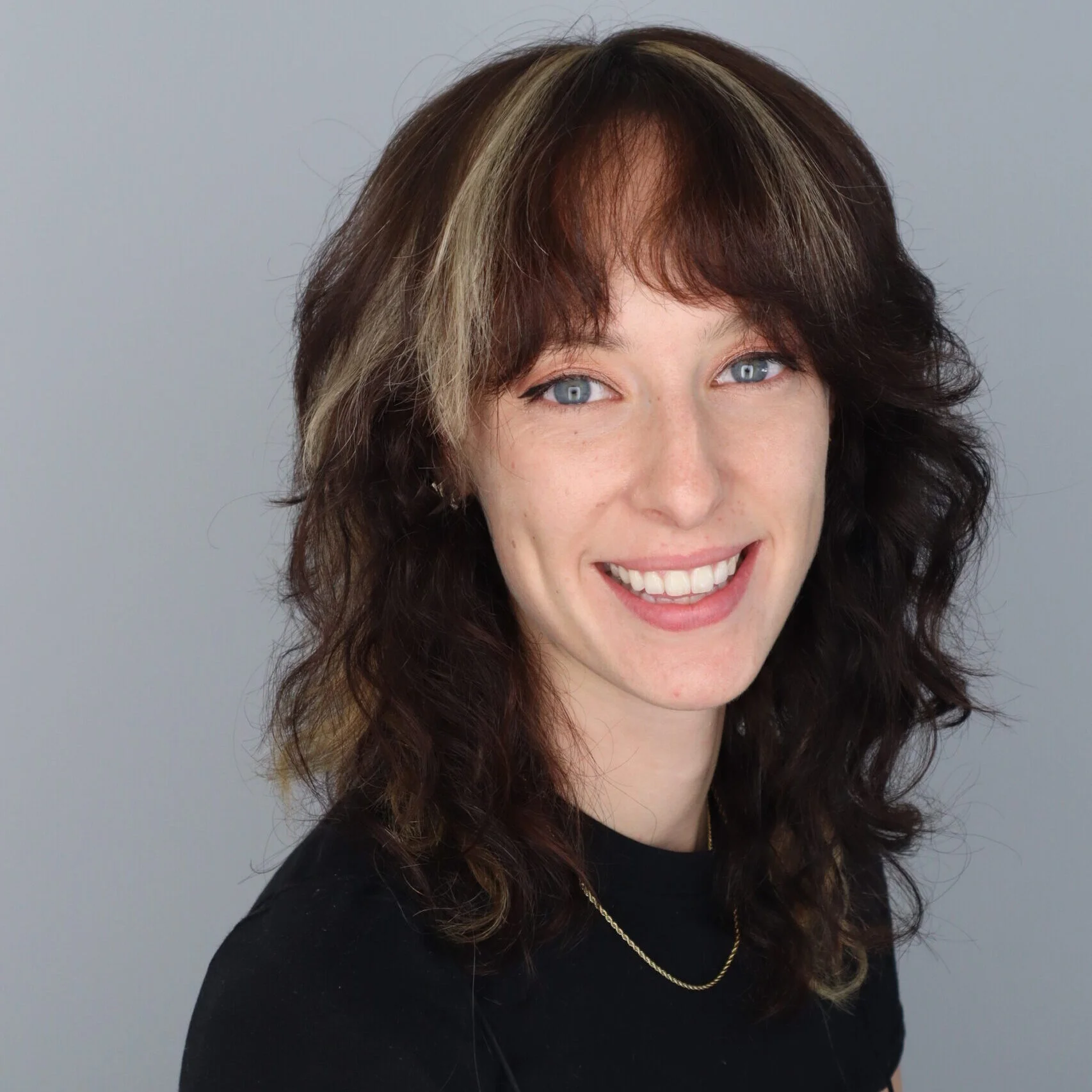 Headshot of Caitlin Norris with a grey background.