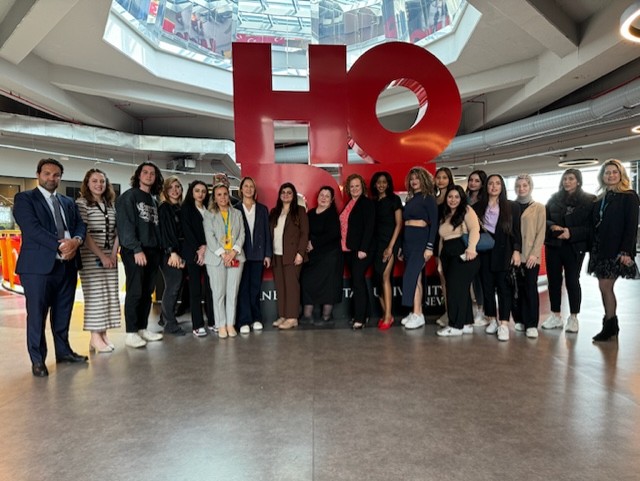 A group of people standing in front of a large red sign.