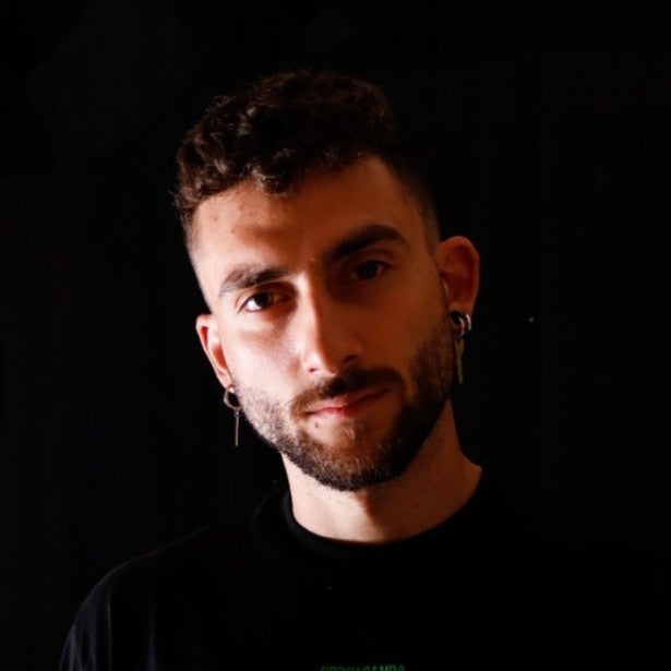a headshot of Dr. Claudio Battiloro. the left side of his face is in shadow. the background is black and he is wearing a black shirt.