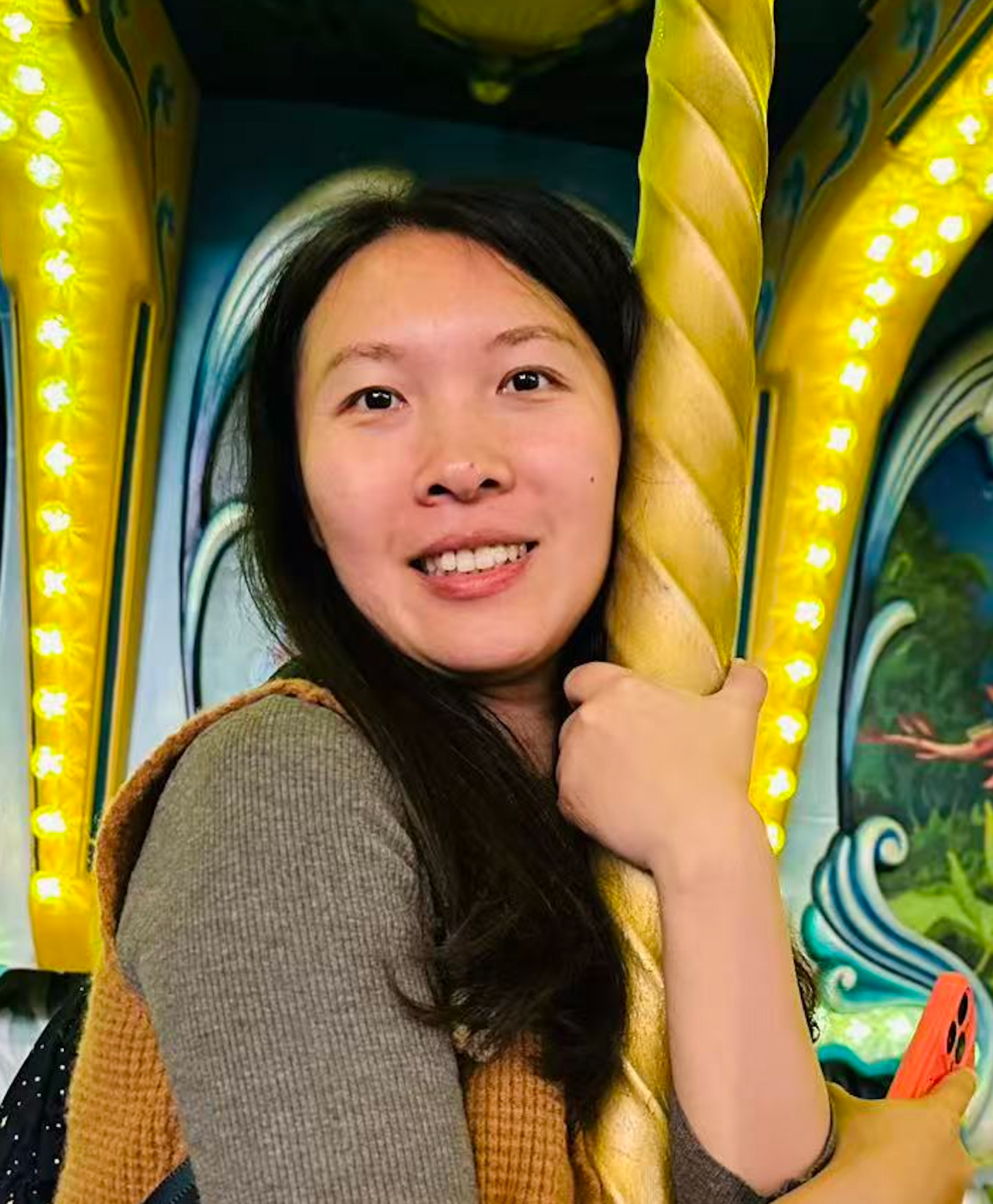 a headshot of Dr. Ting Zhang. She is holding onto a carousel stability pole.