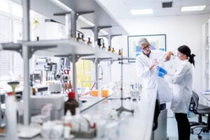 Two laboratory technologists seen working with some medical bottles, tubes and pipettes during an experiment.