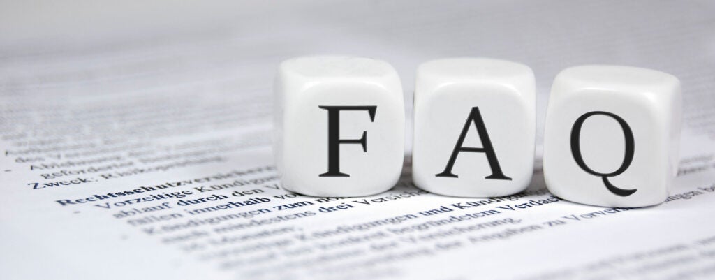 Three white dice with the letters "F", "A", and "Q" on them, placed atop a document with text, symbolizing frequently asked questions.