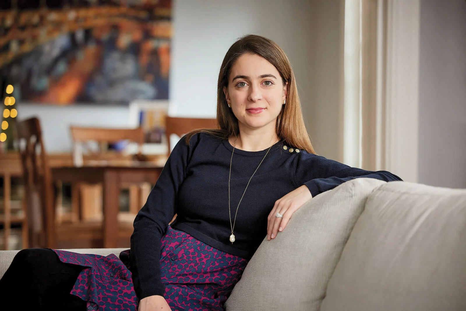 Antonella Lisanti-Park poses with her arm on the back of a cream couch.