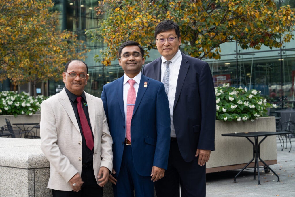 2024 Alumni Award of Merit winners in a stone courtyard with flowering planters. 