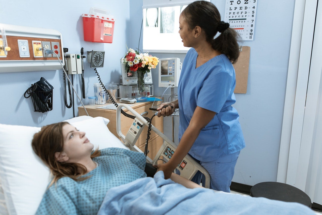 Nurse helps patient in a hospital bed
