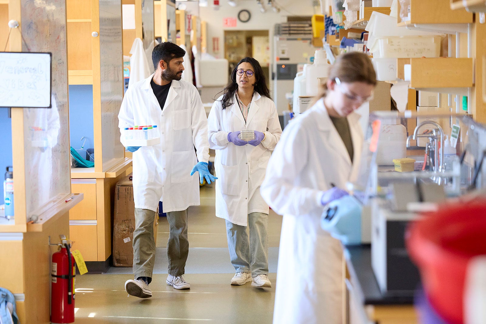 People walking down hallway in white lab coats.