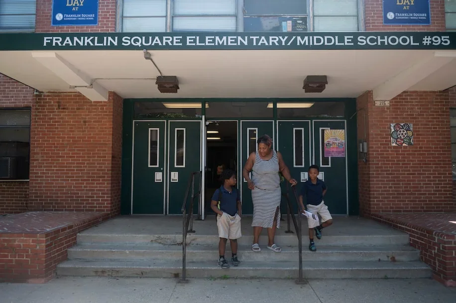 A woman and two children walk out of Franklin Square Elementary School