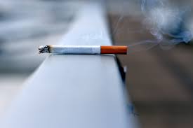 A smoking cigarette lying on a ledge.