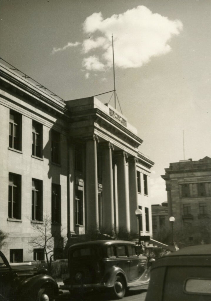 Black and white shows a neoclassical building with an old automobile parked in front. From the Archives of the Harvard T.H. Chan School of Public Health.