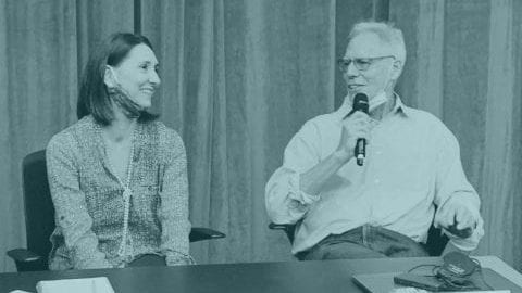 Photo of Professor James Robins on stage in discussion with a colleague.