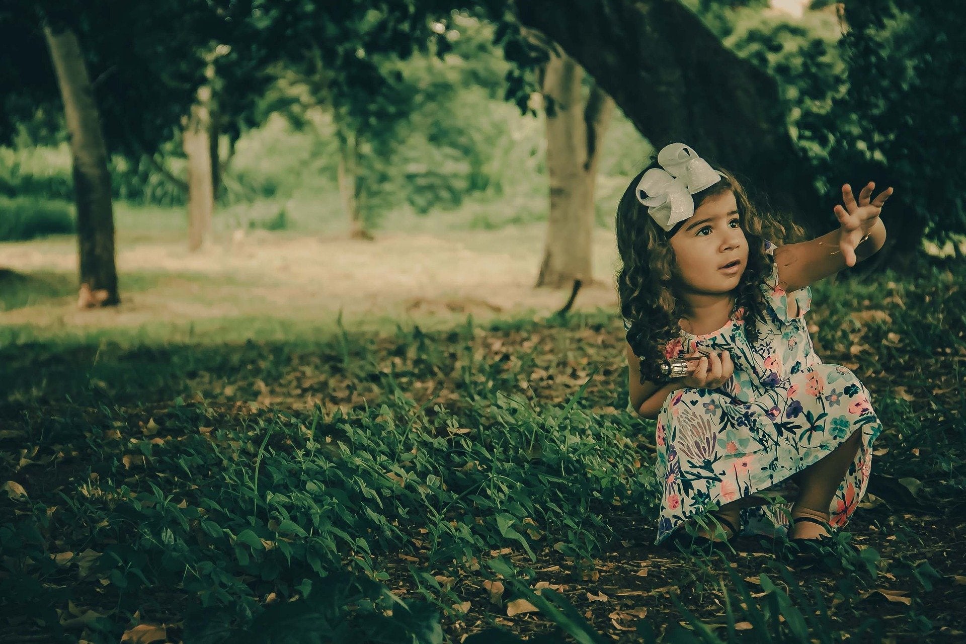 Girl crouching under tree