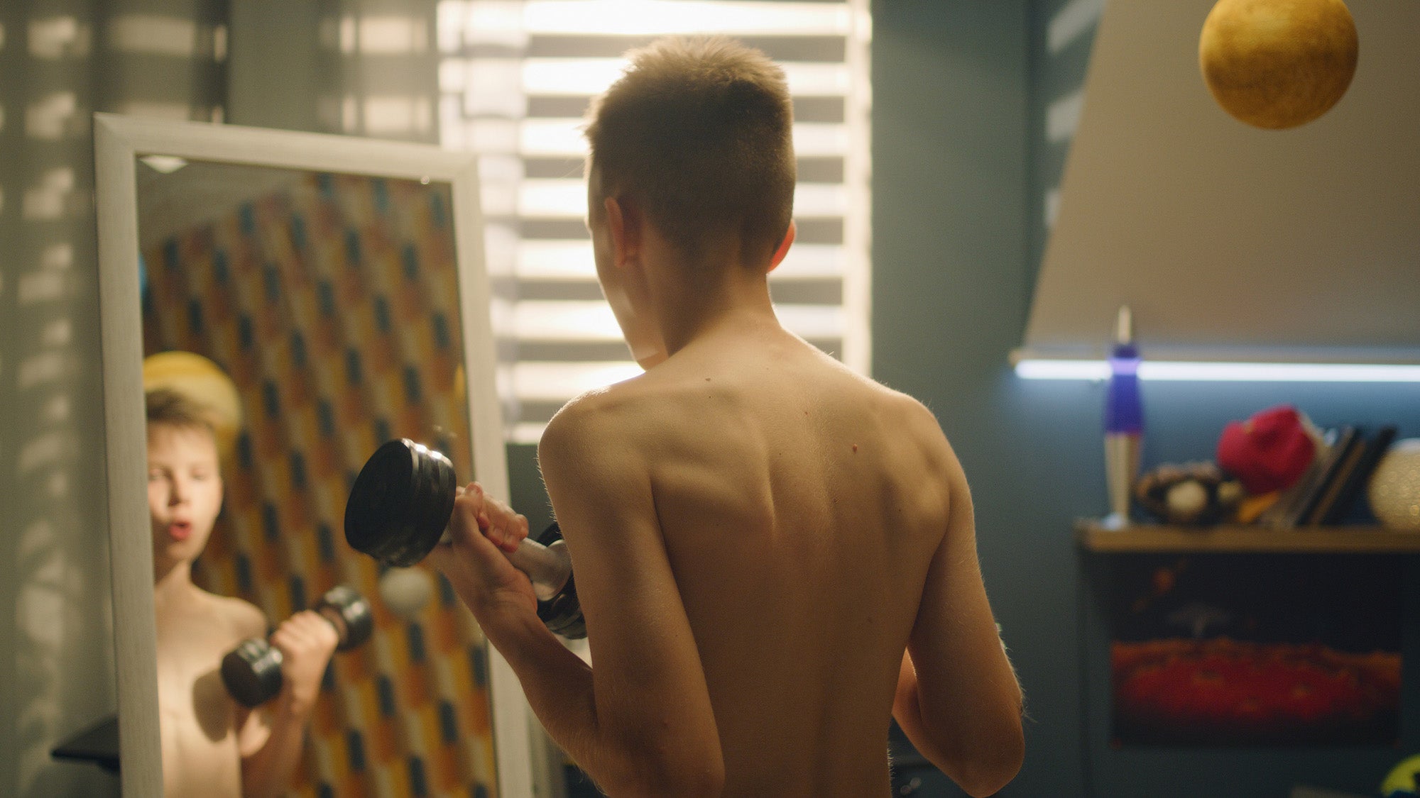 Teen boy using dumbbells.