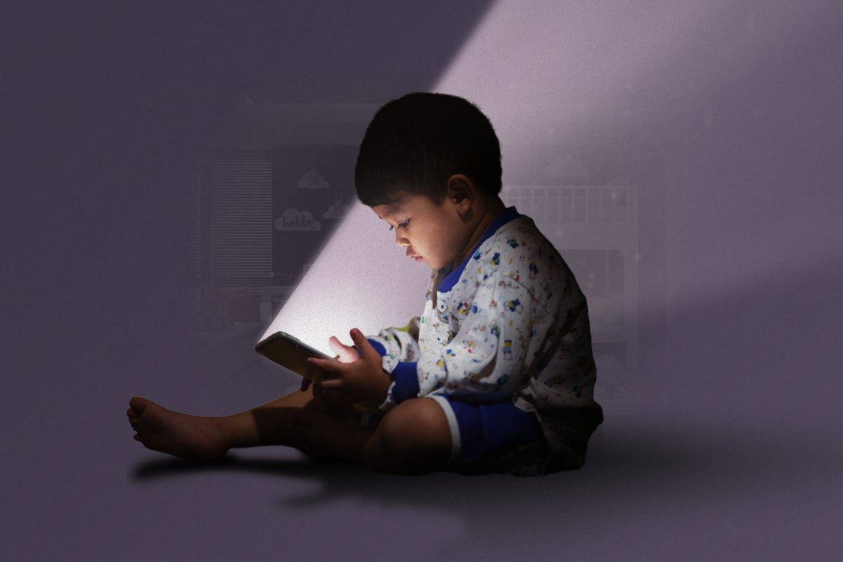 Child interacting with a tablet device. The light from the screen is illuminating their face