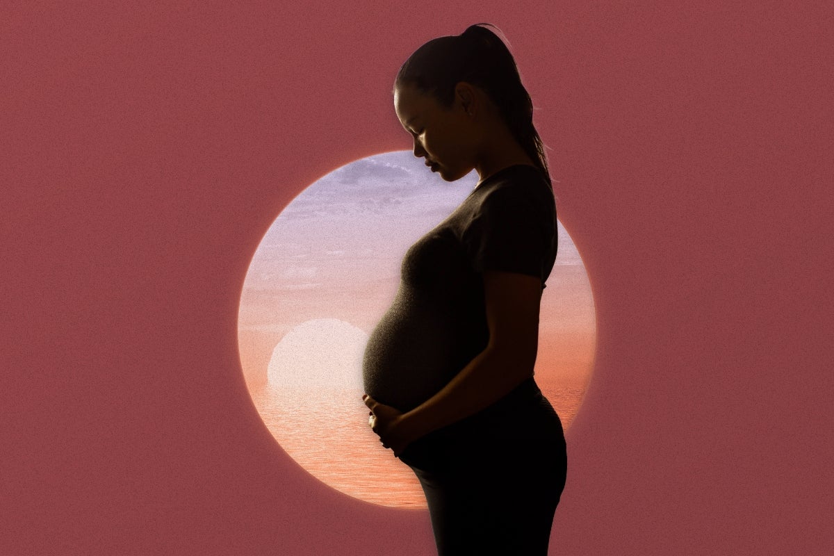 Profile of a pregnant woman holding her stomach with a sunset behind her