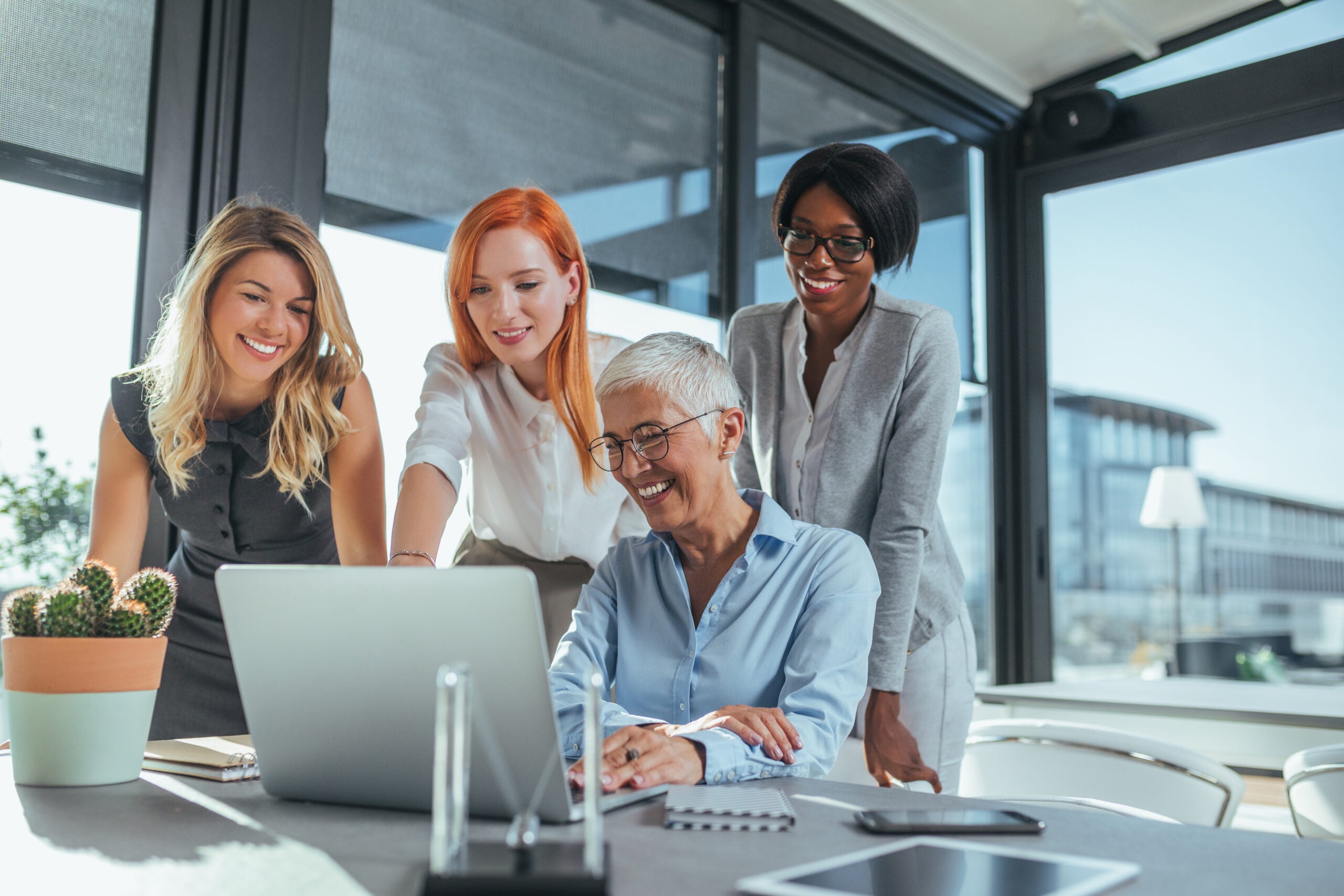 Group of professional women at table looking at computer