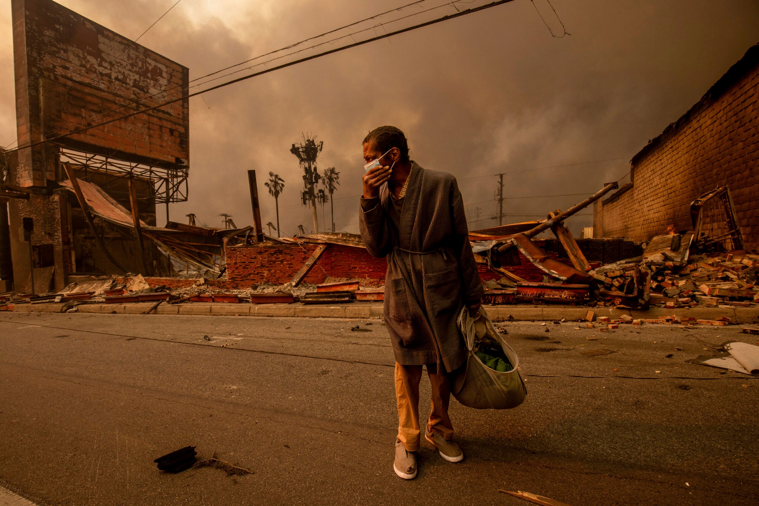 A man walks past a fire-ravaged business after the Eaton Fire swept through Wednesday, Jan. 8, 2025 in Altadena, Calif.